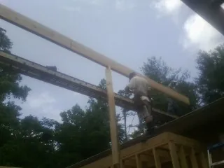 Carpenter setting a ridge beam over a new addition frame — Ice Dam Removal by Roofing Brothers in Benson