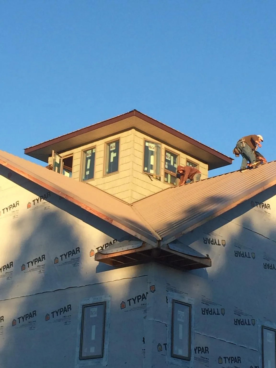 Roofers working around a rooftop cupola on a new metal roof at sunset — Roof Waterproofing in Benson by Roofing Brothers
